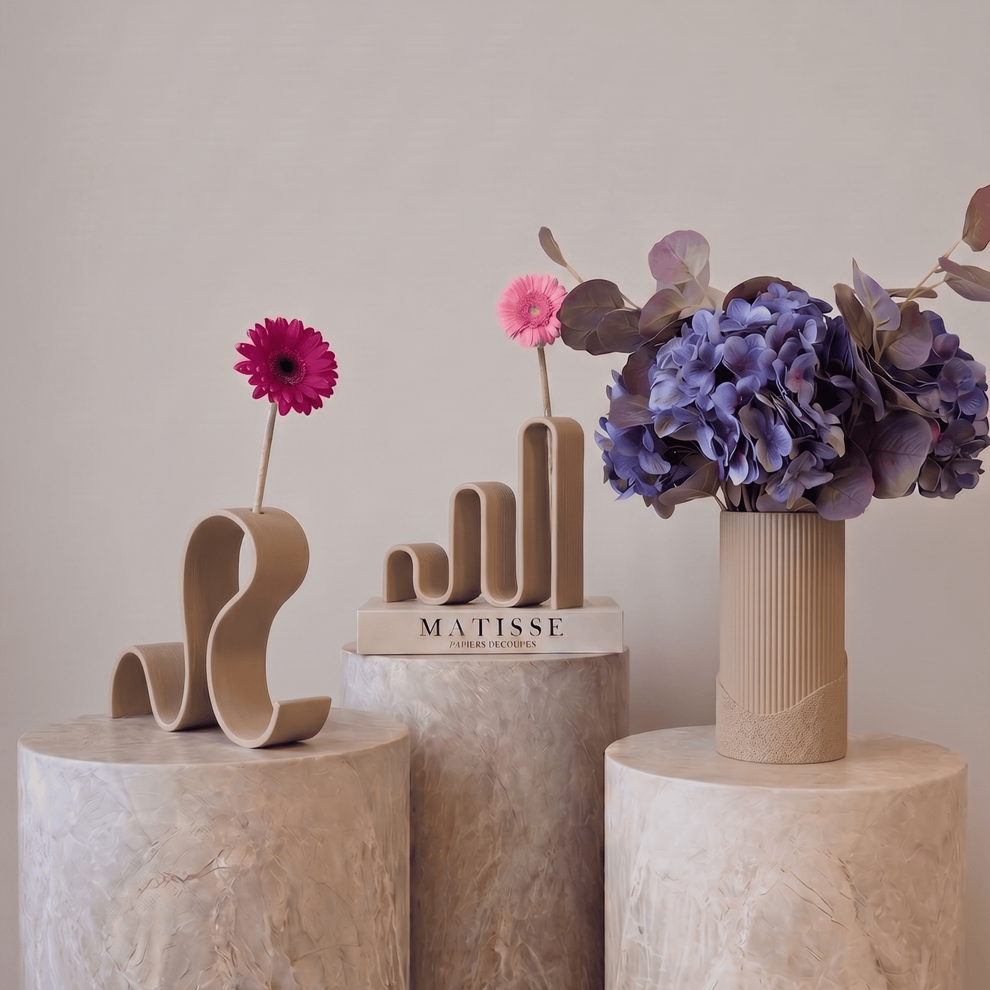Colecția Vernisaj în crem texturat, vaze decorative Antiform cu forme ondulate, gerbera roz și aranjament de hortensii