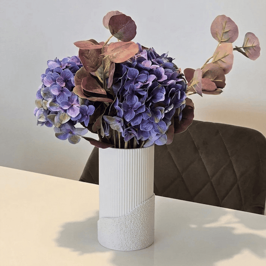 Vaza decorativă Fluora albă, cu buchet de flori uscate, pe masă într-un living luminos